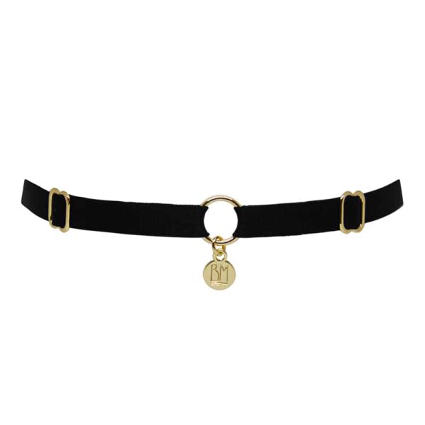 Ici vous pouvez voir le BRIGADE MONDAINE GIFT WRAP BLACK. Ce collier est fait d’une bande noire. 2 détails pour régler les bandes se trouvent à droite et à gauche. Au milieu, la bande est séparée par un anneau plaqué or avec un pendentif ou il est inscrit « BM ».