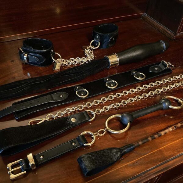 Коллекция бондажа, состоящая из наручников, d'кнута секстоя, d'чокер, d'поводка, d'кляпа и d'кнута.