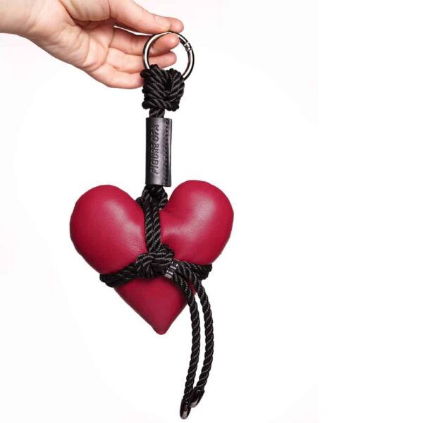 Llavero en forma de corazón rojo sostenido por cuerdas negras