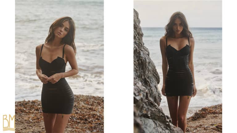 Fotos in amerikanischen und italienischen Farbaufnahmen, aufgenommen von Jean Marc BULLES für Brigade Mondaine von Model Elsa Couturier in einem schwarzen Kleid Angela aus Bordelle, erhältlich bei Brigade Mondaine, mit einer Strand- und Meereslandschaft im Hintergrund.