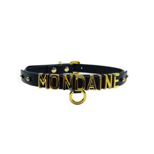 Collier / choker en cuir noir italien souple avec accroche et lettres en or plaqué 24 carats et une petite pierre incrustée sur chacune des lettres écrivant le mot MONDAINE de la collection UPKO X Brigade Mondaine disponible chez Brigade Mondaine