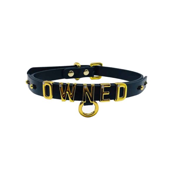 Collar / choker in soft black Italian leather with 24 carat gold-plated hook and letters and a small stone inlaid on each of the letters writing the word OWNED from the UPKO X Brigade Mondaine collection available at Brigade Mondaine