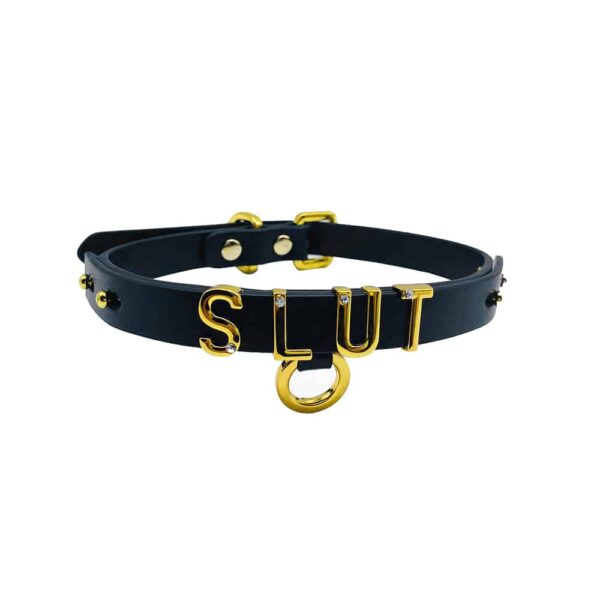 Collier / choker en cuir noir italien souple avec accroche et lettres en or plaqué 24 carats et une petite pierre incrustée sur chacune des lettres écrivant le mot SLUT de la collection UPKO X Brigade Mondaine disponible chez Brigade Mondaine