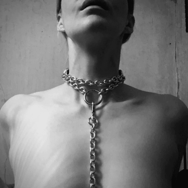 Photo noire et blanche d’une femme nue avec collier laisse de chaines