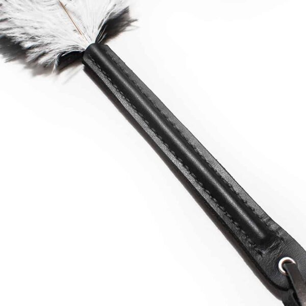 black and white ostrich feathers on black leather handle, the whole object measures 45cm and the feathers 25cm