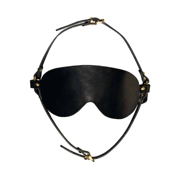 Blinde BDSM-Maske Arien von der Marke Elif Domanic. Diese Maske ist komplett aus schwarzem Leder gefertigt und verfügt über eine dicke Brille mit einem mit Nägeln verzierten Kopfband. Dazu kommt ein weiteres Kopfband, das vom Schädel bis zum Kinn reicht, ebenfalls aus schwarzem Leder, das mit einer dünnen Schnalle am Kinn befestigt wird. Das Ganze wird durch zwei Ringe an den Ohren verbunden.