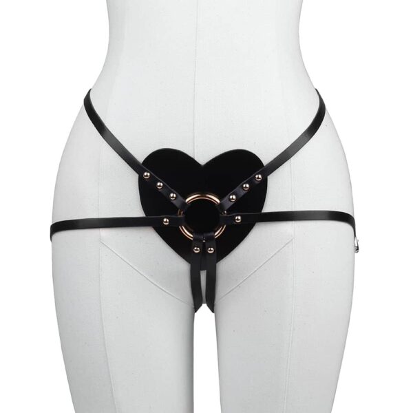 Harness black leather from Elif Domanic. This harness has an elegant leather heart placed at the level of the lower abdomen with in its center a golden brass ring which gathers the straps placed on the lower back and for the turns of thighs. Fine buckles and a few gold coloured studs are placed on both sides of the product.