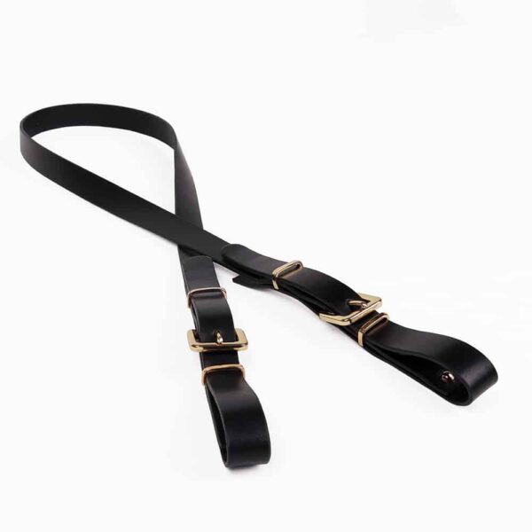 Black leather strap with golden studs and buckles by Elif Domanic. This strap is part of a head harness and its purpose is to pull the head.