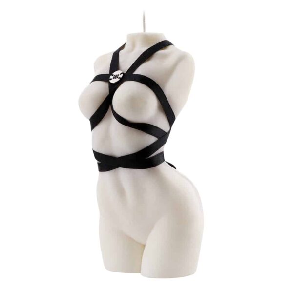 Candle of the brand Baed Stories. This white candle represents the body of a naked woman arched and without arms. A black ribbon wraps around the body so that it forms a harness around the breasts, waist and neck. The silver Baed Stories logo is sewn onto the harness at chest level.