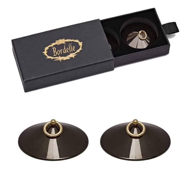 Black O gunmetal nippies by Bordelle. This pair of nippies is metallic plated with a 24 carat gold plated ring. The product is simple with the conical black metallic part and at the top a small gold ball with a hanging ring. The product packaging is also present with a cardboard box embossed with the brand's logo and a velvet interior with two spaces dedicated to storing the product.