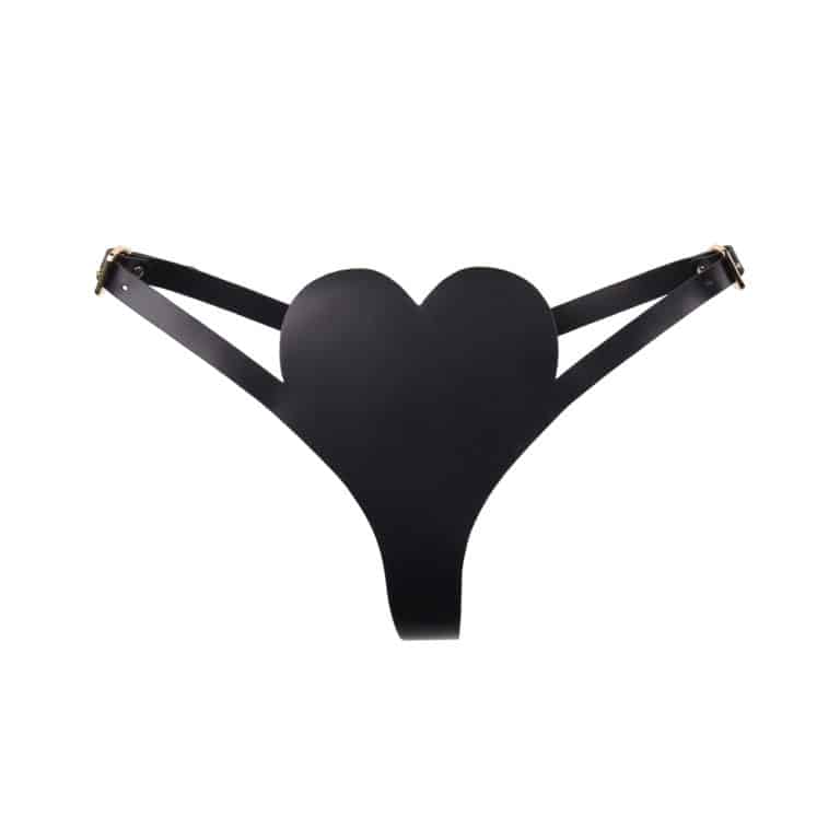 Black thong by Elif Domanic. This leather harness thong is black in color and features a heart shaped piece for the lower stomach. A leather hip band connects the whole in one piece with gold coloured adjustments on each hip. Behind, a ring placed at the level of the buttocks connects the string to the hip band. The backside is decorated with small studs.