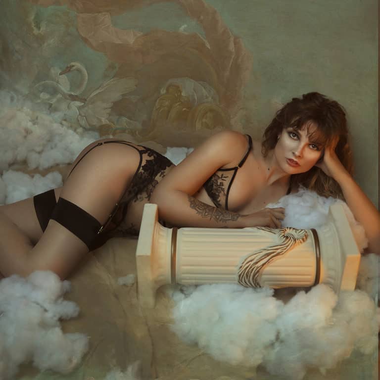 Lingerie set from the brand HERVÉ by Céline Marie with a triangle bra and suspender belts whose shape is ensured by black velvet elastics and a transparent fabric decorated with black lace. The clasps of the garter belts and bra rings are golden.