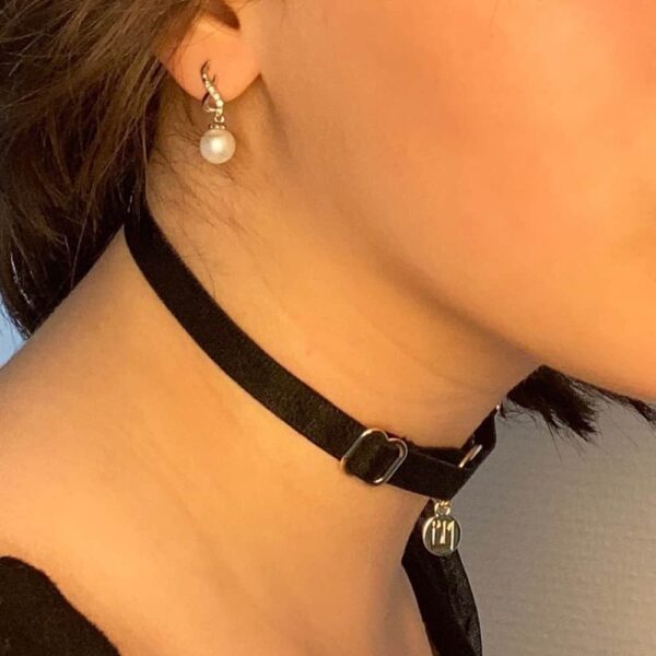 BM-Halsband ist im Brigade Mondaine-Geschenkpaket enthalten. Das Produkt ist ein einfacher Choker mit einem Halsband aus schwarzem Gummiband und einem goldenen Anhänger, der mit dem Brigade Mondaine-Logo geprägt ist. Dieser Schmuck ist mit einem Ring am Halsband befestigt. Das gesamte Produkt ist verstellbar.