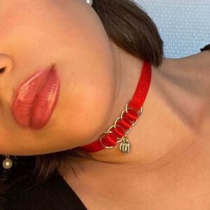 BM necklace included in the Brigade Mondaine gift pack. The product is a simple choker with a red elastic necklace and a gold pendant embossed with the Brigade Mondaine logo. This jewelry is attached to the choker by four rings supported by the intertwining elastic. The whole product is adjustable.