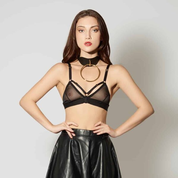 Leather Artefact Chocker O Black from ELF ZHOU LONDON. The chocker is black leather and has in the center of it a large gold buckle. The model wears a black transparent triangle support and a black leather skirt. She stands with her arms on her hips and looks at the camera.