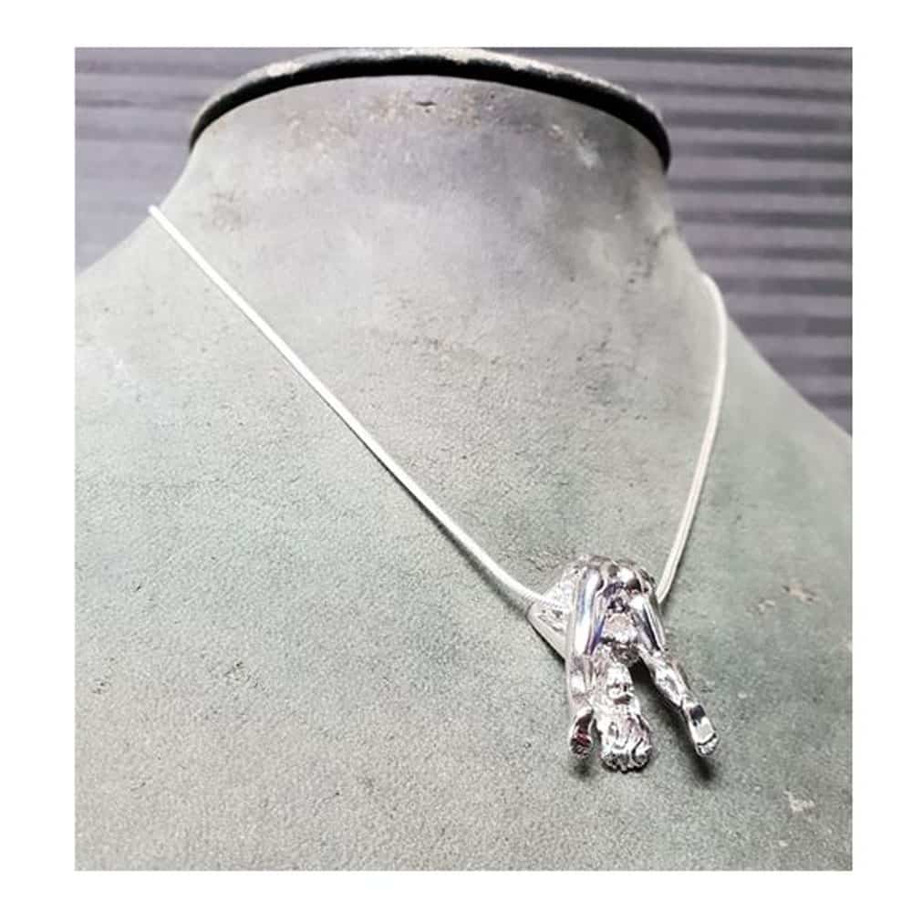 Silberne Halskette Rosebuds, die eine Frau in Silber besitzt, die uns ihre Anatomie zeigt, in der Tat hat sie ihre Beine in der Luft gespreizt.