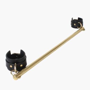 Spreader bar of the brand Elif Domanic. Two handcuffs with a gold colored buckle support a long and thin bar by two rings