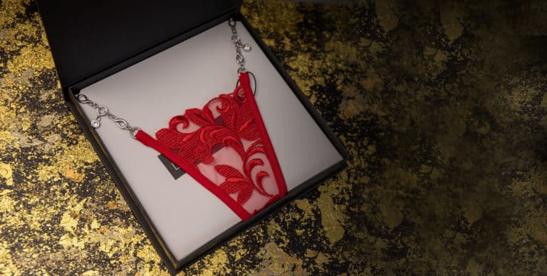 Ювелирные стринги LOVE STORY от LUCKY CHEEKS, изготовленные в Германии со швейцарской вышивкой, красным тюлем и цепочкой zamac серебряного цвета, поставляются в элегантной подарочной коробке.