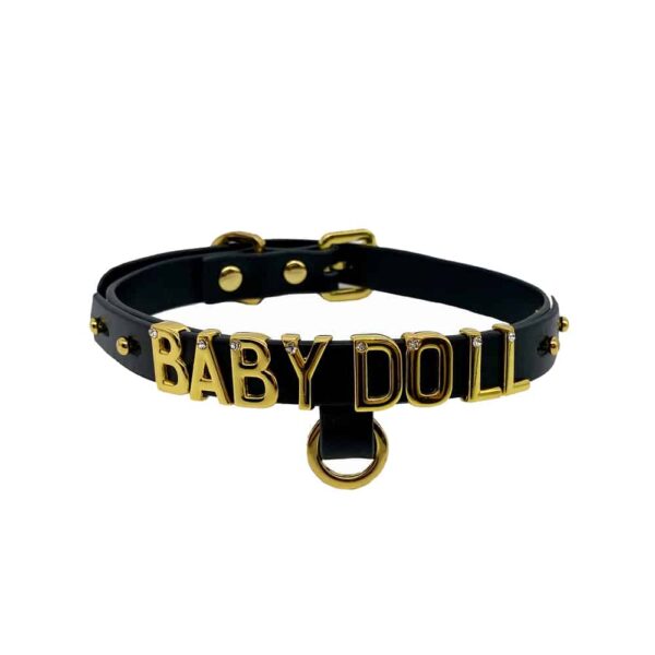 Collar / gargantilla en suave cuero italiano negro con gancho y letras bañadas en oro de 24 quilates y una pequeña piedra incrustada en cada letra que escribe la palabra BABYDOLL de la colección UPKO X Brigade Mondaine disponible en Brigade Mondaine