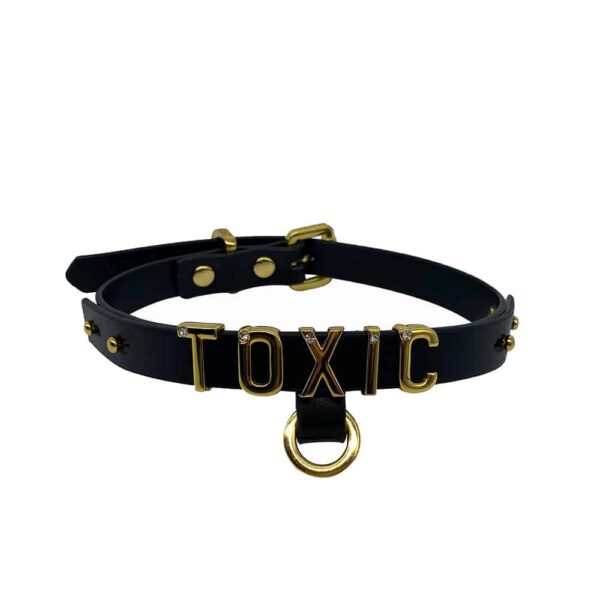 Halskette / Choker aus weichem schwarzem italienischem Leder mit Haken und 24 Karat vergoldeten Buchstaben und einem kleinen eingelegten Stein auf jedem der Buchstaben schreiben das Wort TOXIC aus der Kollektion UPKO X Brigade Mondaine erhältlich bei Brigade Mondaine