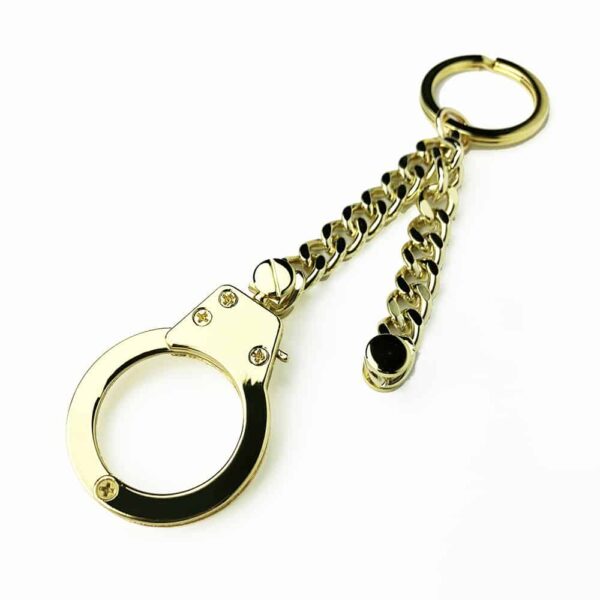 Schlüsselanhänger aus Leder mit Handschellen der Marke ELF ZHOU LONDON. Der Schlüsselanhänger enthält eine goldene Kette, an deren Ende sich geschlossene Handschellen befinden.