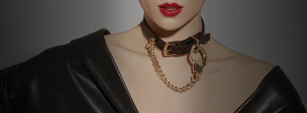 Halskette Handschellen Ketten und Leder von der Marke ELF ZHOU LONDON. Die Halskette ist um den Hals des Models gebunden. Der Lederteil der Halskette ist befestigt und die Goldkette, die durch die goldene Handfessel mit der Halskette verbunden ist, hängt herunter.