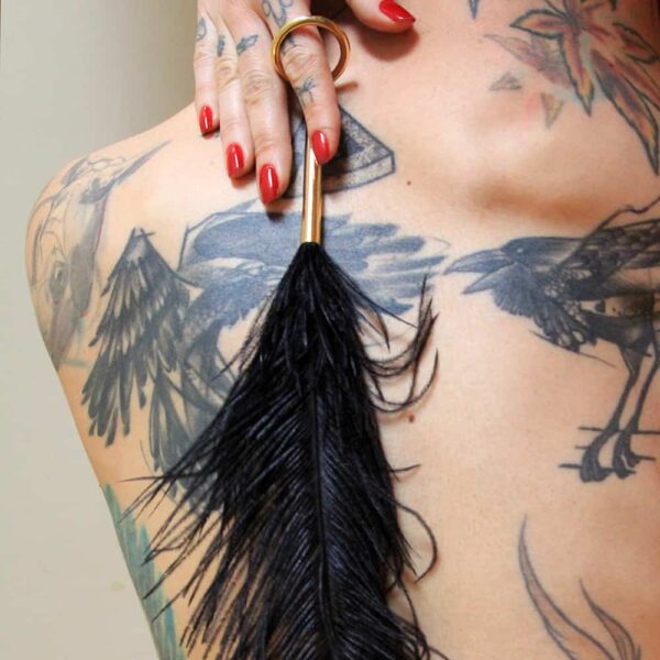 Teaser de plumas de avestruz de Elif domanic. El teaser es de color negro. En el extremo de la pluma hay una fina asa circular de oro y en el extremo una pequeña hebilla de oro.