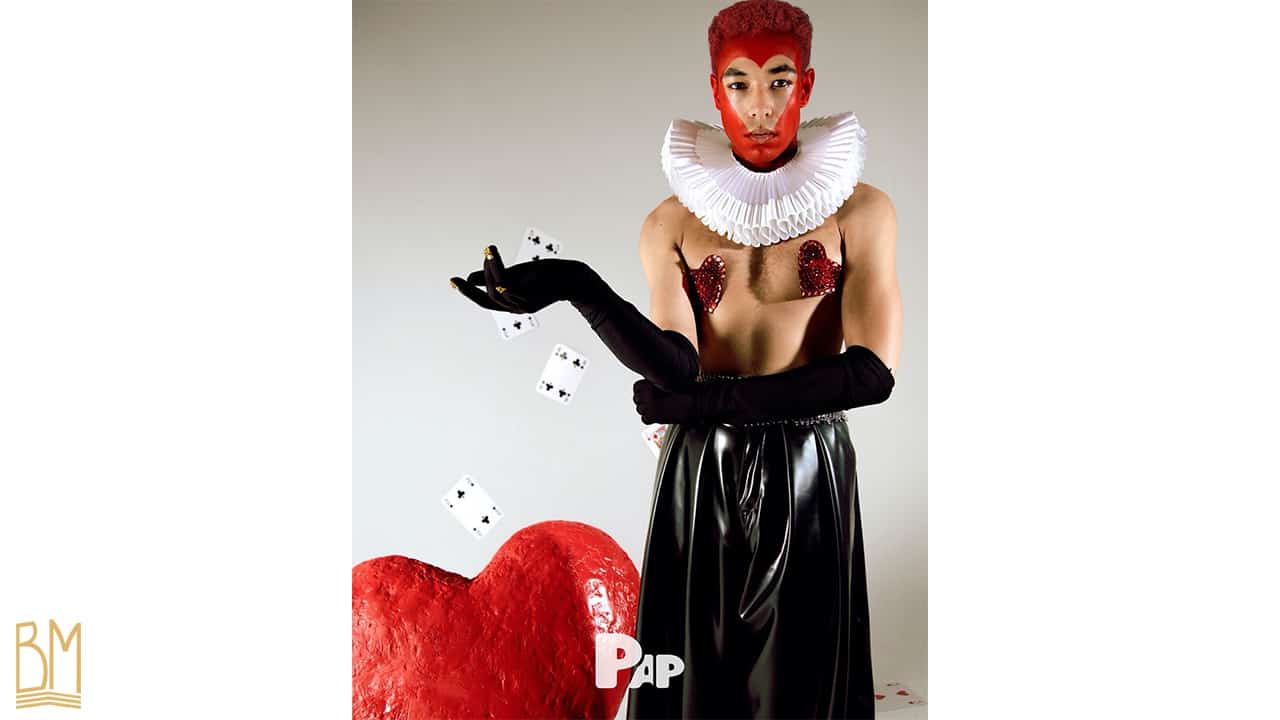 PAP Magazine es handelt sich um einen Mann, der Karten wirft. Sein Gesicht ist rot bemalt und bildet das Zeichen des Herzens. Er trägt schwarze Handschuhe, die bis zu seinen Unterarmen reichen, sowie Nippies der Marke Ruth Melbourne. Hinter ihm befindet sich ein großes rotes Herz.