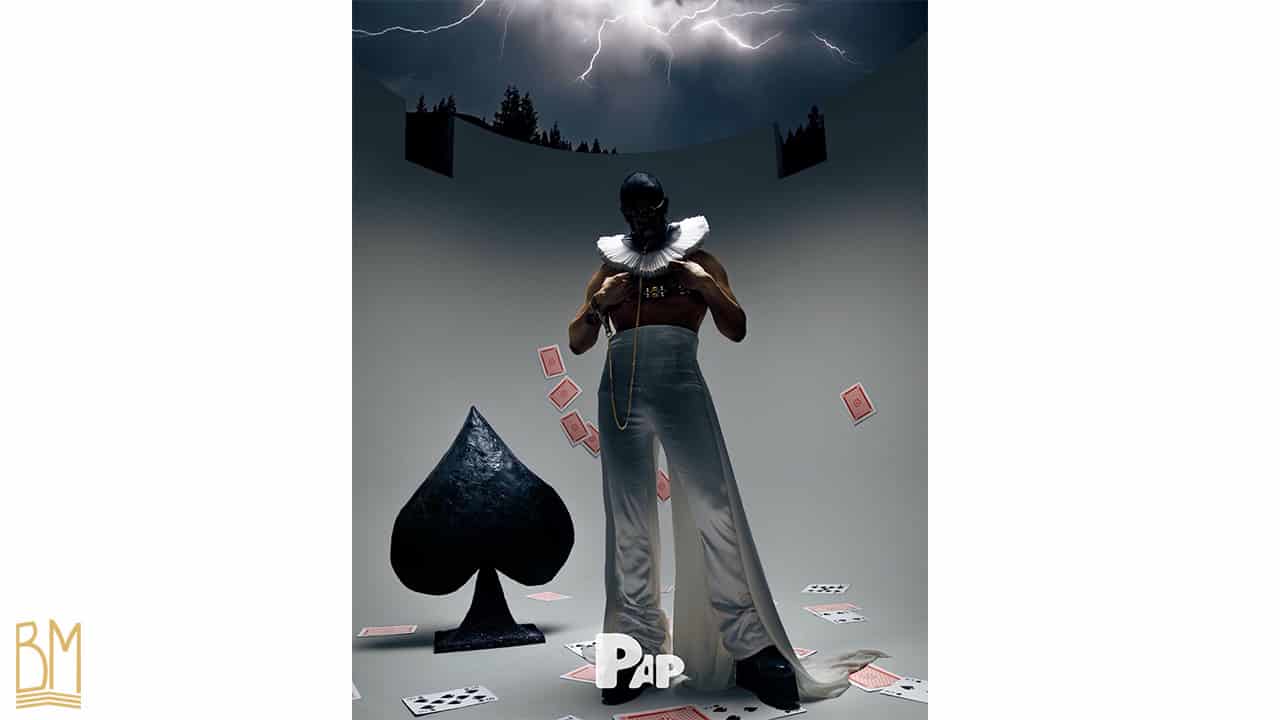 PAP Magazine it is a man wearing a leash of the brand Upko. Behind him is the black spade sign. To his left are falling cards and on the ground are scattered cards.