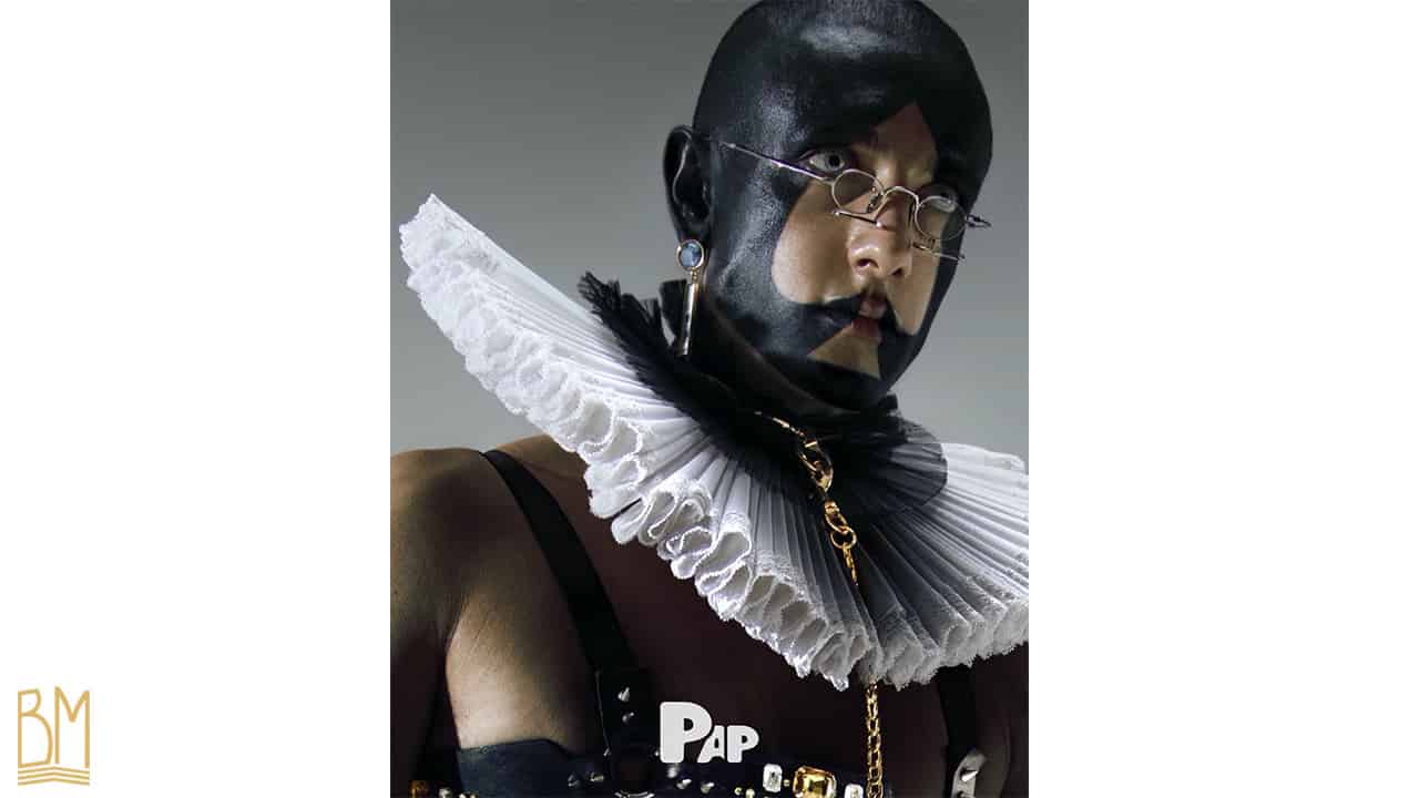 PAP Magazine il s’agit d’un homme portant une laisse de la marque Upko. Son visage est peint en noir et forme le signe du pique