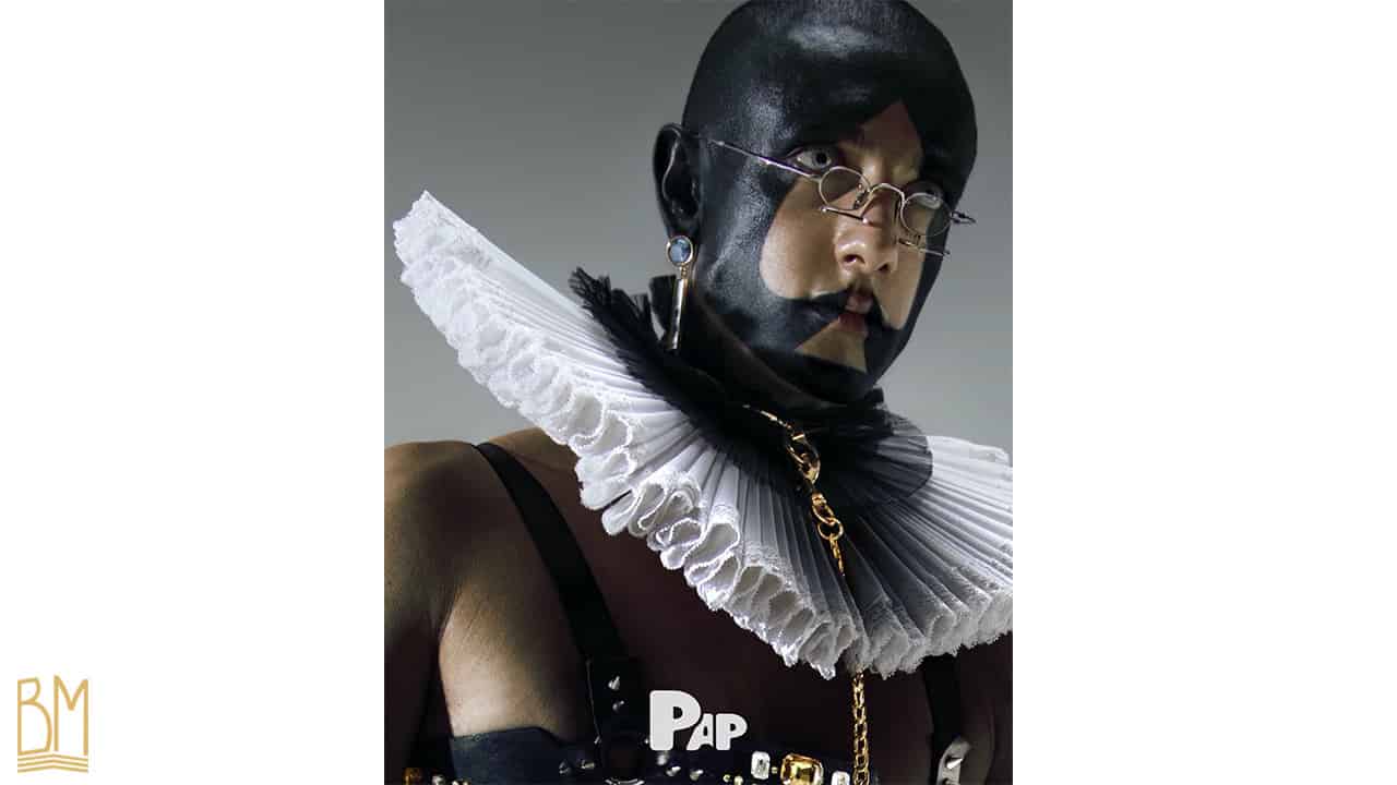 PAP Magazine it is a man wearing a leash of the brand Upko. His face is painted in black and forms the sign of the spade