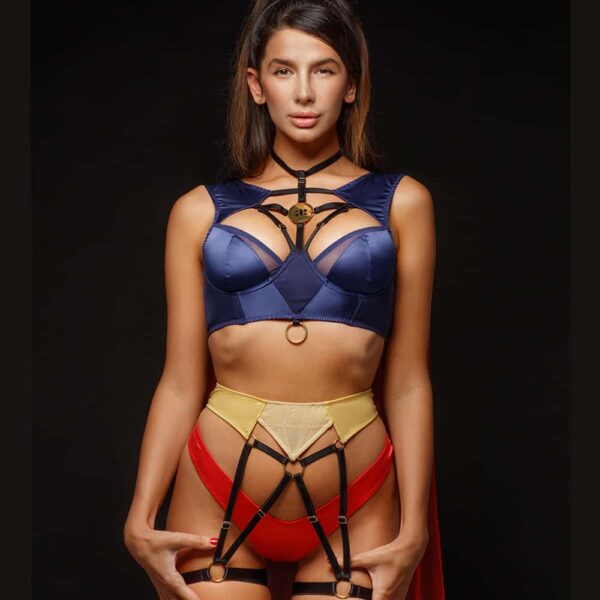 Role Play Costume SuperWoman de la marque BAED STORIES. L’ensemble est bleu, jaune, rouge et noir sur les lanières est composé d’un soutien-gorge bleu marine avec un anneau et d’une amulette dorés. La culotte et la cape transparente sont rouges. Le porte jarretelle jaune est attaché aux jarretelles en élastiques.