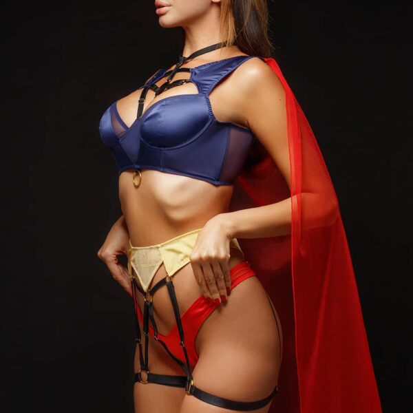 Role Play Costume SuperWoman of the brand BAED STORIES. The set is blue, yellow, red and black on the straps is composed of a navy blue bra with a gold ring and amulet. The panties and the transparent cape are red. The yellow garter belt is attached to the elastic suspenders.