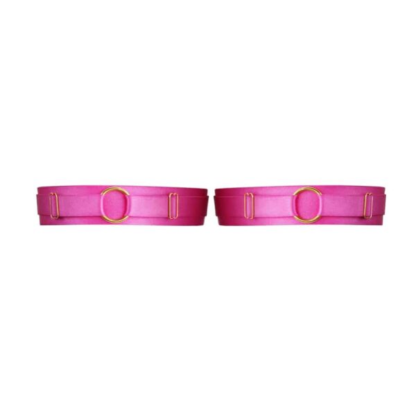 Matrix pink garters from Kaimin. The product is made from a thick elastic on the front decorated with a ring in its center. In the back three small bands are connected by small gold hooks.