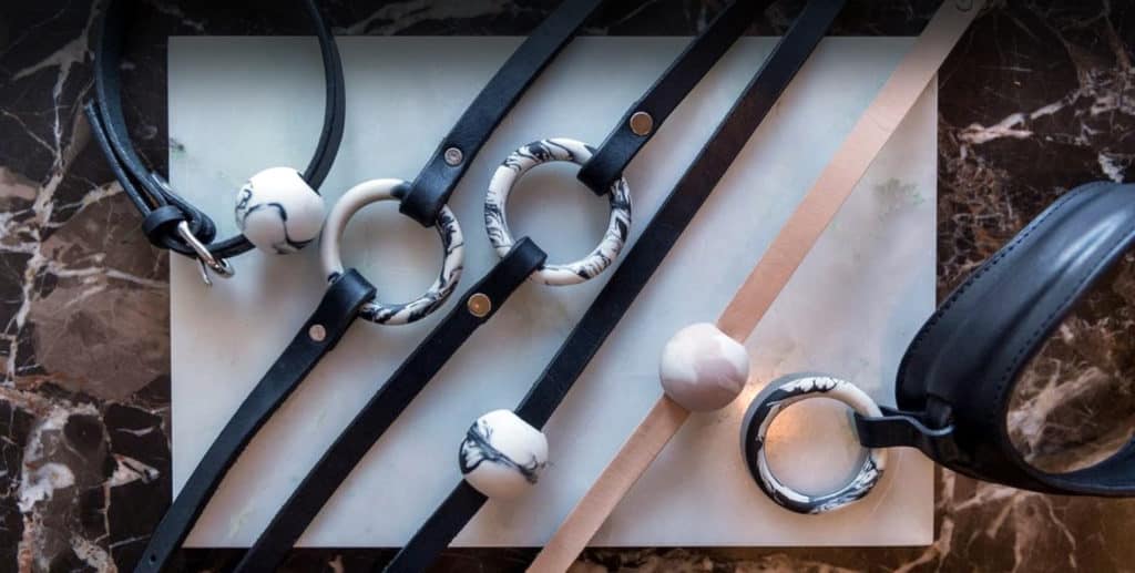 Lederhalsband in schwarz und beige, dünnes Band und ein dickes Halsband. Auf jedem Halsband befindet sich ein Ring oder eine Kugel mit einem Marmormuster.