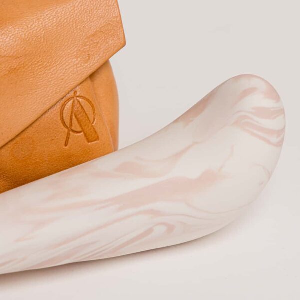 Orange leather pouch with the brand's logo on it. The thick spur on the top and thinner tip, it is porcelain colored pink and white from Adeles Brydges at brigade mondaine