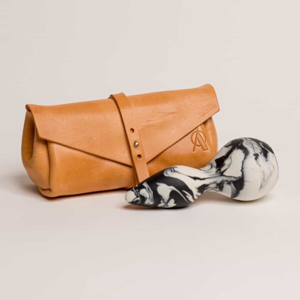 Pochette en cuir orangé avec le logo de la marque dessus .Plug petit à un embout en pique de couleur noir et blanche de adules brydges chez brigade mondaine.