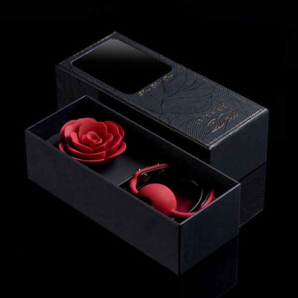 Pink Ball Gag from the brand Upko x Zalo. The product is detached, the back of the product is black and the front is red. The center of the Ball Gag is shaped like a red rose. The whole is placed on a black background.