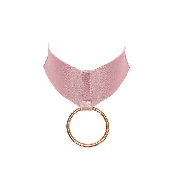 Collar Bondage de la colección Kora de Bordelle. Este collar es de color rosa. Se compone de una banda elástica ancha con un anillo colgante chapado en oro de 24 quilates en su centro. El anillo se mantiene en su sitio mediante una banda elástica más fina yuxtapuesta a la banda elástica ancha.