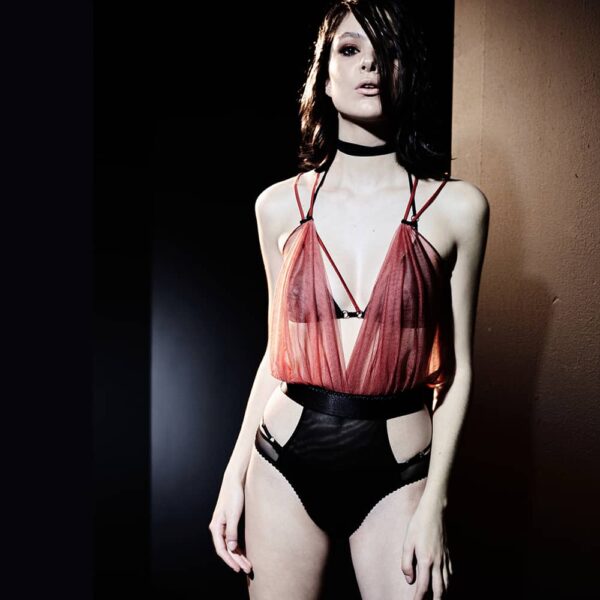 Bodysuit Incense Collection Caravasar of the brand Gonzales Affaires. This bodysuit is composed of two colors. First of all red that covers the chest to the waist. This part of the product is made of transparent tulle and is worked in the form of a drape that covers the chest. A wide black elastic belt divides the product and reveals the fabric that covers the belly and intimate parts in the form of single panties. A double strap is connected to the bodysuit.