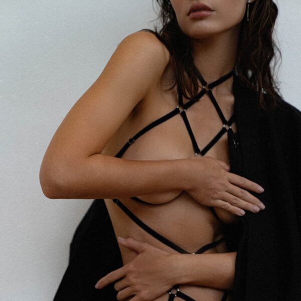 Les rubans de velours et les anneaux en métal créent un motif symétrique intéressant sur votre corps qui souligne les courbes naturelles. Le playsuit noir est fait avec des détails dorés.