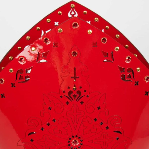 La mitre confessionnelle est entièrement réalisée à la main et sur commande à Berlin, dans les ateliers de la marque, à partir de cuir verni rouge découpé au laser et de rivets en or rouge ; la Mitre confessionnelle Rosso en cuir rouge incrusté de SWAROVSKI® est un accessoire fetish de luxe extraordinaire.