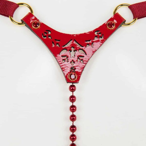 The red rosso pearl thong is entirely handmade and made to order in Berlin, in the brand's workshops, from laser-cut red patent leather and red gold rivets; The Rosso Pearl Thong encrusted with SWAROVSKI® is designed to be seen. Chic & Seductive! The center string features a luxurious strand of black glass beads and adjustable double-sided satin elastic for easy waist adjustment. Guaranteed to stimulate your senses! Custom laser-cut red patent leather Red crystal rivet center chain Adjustable double-sided satin elastic for easy size adjustment Gold SWAROVSKI® Red Siam Crystal rivets