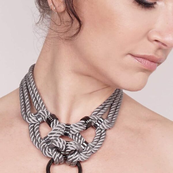 "Megami" means goddess in Japanese. This choker necklace will not leave anyone indifferent, both by its manufacture from waxed cotton rope and tied symmetrically, as well as by its design of intertwined knots with silver finishes. Closing on the neck. One size fits all & adjustable. This necklace is available at Brigade Mondaine.