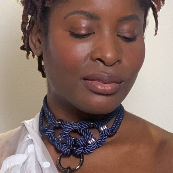 "Megami" means goddess in Japanese. This choker necklace will not leave anyone indifferent, both by its manufacture from waxed cotton rope and tied symmetrically, as well as by its design of intertwined knots with silver finishes. Closing on the neck. One size fits all & adjustable. This necklace is available at Brigade Mondaine.