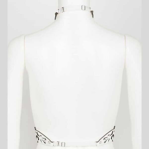 Harness from the Original Sin Bianco collection by Fraulein Kink on Brigade Mondaine. Entirely handmade and made to order, in the brand's Berlin workshop, from laser-cut patent leather, the Bianco Harness will leave no one indifferent during your fetish or erotic parties. An original bust harness by its design and very detailed thanks to its laser cuts and its finishing with high quality crystal rivets. Designed to flatter, you can wear this glamorous piece over your favorite silk blouse, dress or directly on the skin. A perfect accessory for inside or outside the bedroom, all eyes will be on you! Laser-cut straps and bodice in white patent leather. Pearly silver ivory double-capped rivets Adjustable ivory double-sided satin elastic straps. Adjustable stretch back hook closure.