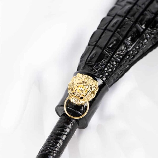 The Croco Martinet from Fraulein Kink. Excite and tease with the ultimate bedroom accessory! The Crocco Flogger is handcrafted from a blend of Italian crocodile and matte black embossed leathers. The gold lion head and double brass cap rivet add the perfect finishing touch to this kinky high fashion accessory