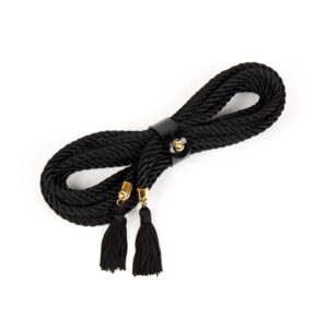 The Ricco Lasso by Fraulein Kink. Bondage lassos have many versatile options for use inside or outside the bedroom. Wear it as a belt or harness to add a high fashion touch to your favorite outfit. 5 yards of black cord. Gold-plated tassel tips. Secured with a patent leather strap with gold button.