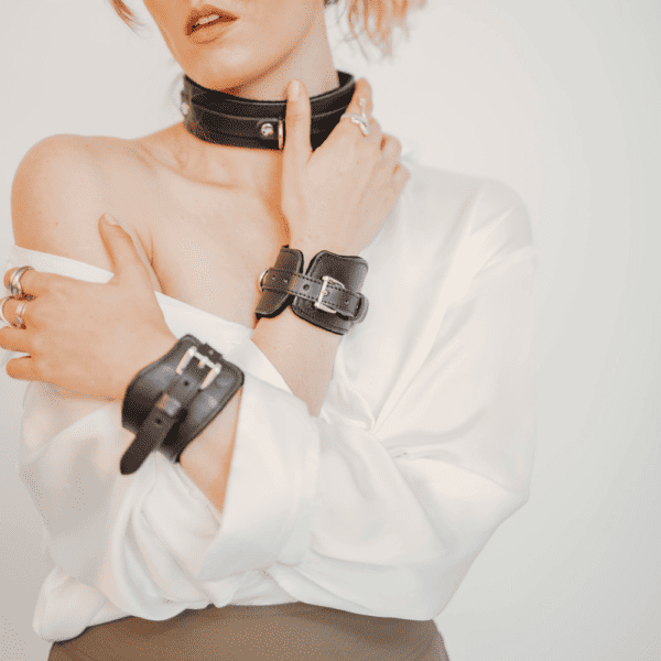 Foto einer Frau, die ein schwarzes BDSM-Lederhalsband mit Handschellen trägt.