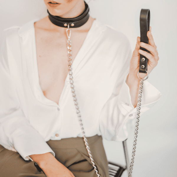Photo d'une femme portant un collier BDSM cuir noir avec une laisse.